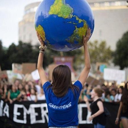 Foto feita em Barcelona, na Espanha, mostra uma ativista do Greenpeace carregando uma réplica do planeta durante um protesto pelo clima - @clau78/The World"s Best Photo of #Photojournalism2020