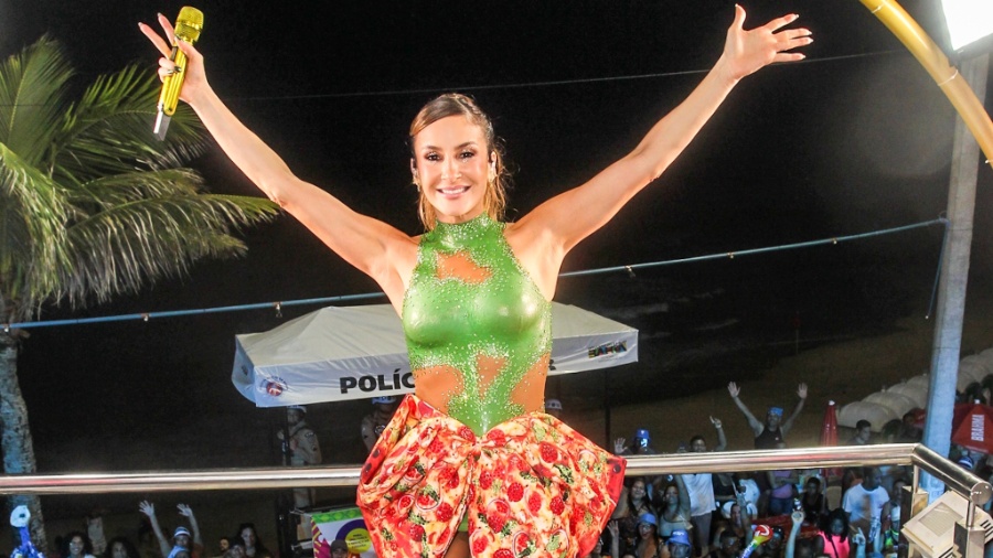 Claudia Leitte posa para foto com braços abertos e público ao fundo, em Salvador
