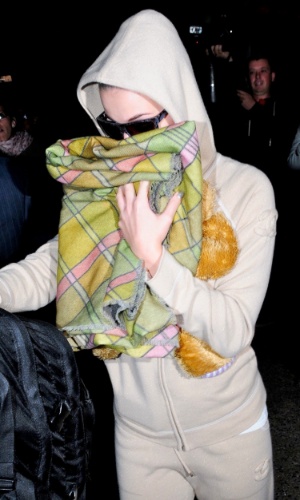 Katy Perry se esconde dos fotógrafos com um cobertor em sua chegada no aeroporto de Los Angeles, EUA (25/3/2012)