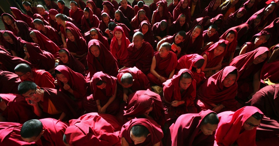 Monges tibetanos se sentam enquanto esperam o corpo de Jamphel Yeshi, dentro do templo Tsuglagkhang, em Dharamsala