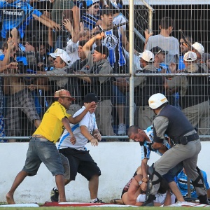 Policial tenta interromper briga entre torcedores na partida entre Grêmio e Pelotas, no domingo - Nabor Goulart/Agência Freelancer