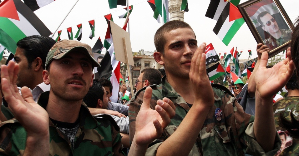 Soldados sírios ?puxam? as palmas durante comemoração oficial em Damasco que lembra o aniversário de fundação do Baath - partido do presidente Bashar al-Assad, que governa o país desde 1963
