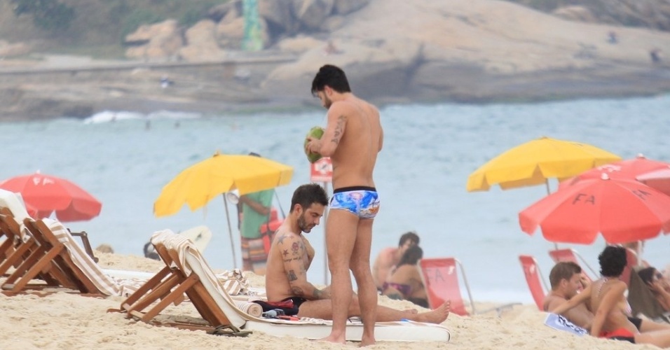 Marc Jacobs (sentado) curte praia acompanhado do namorado, Harry Louis, em Ipanema, zona sul do Rio (9/4/2012)