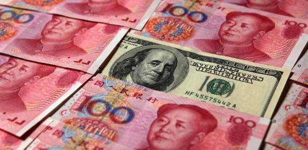 Uma nota de US$ 100 perto de cédulas de 100 yuans - Petar Kujundzic/Reuters
