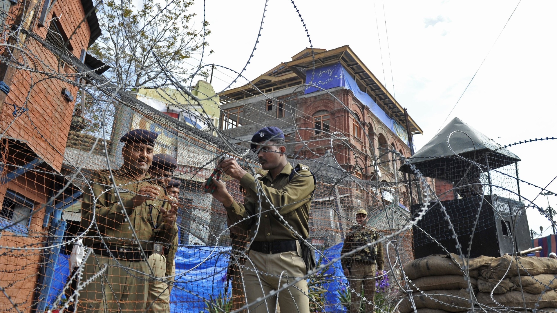 Soldados indianos cortam cerca de arame farpado durante processo de demolição de bunker em Srinagar, na Índia - AFP