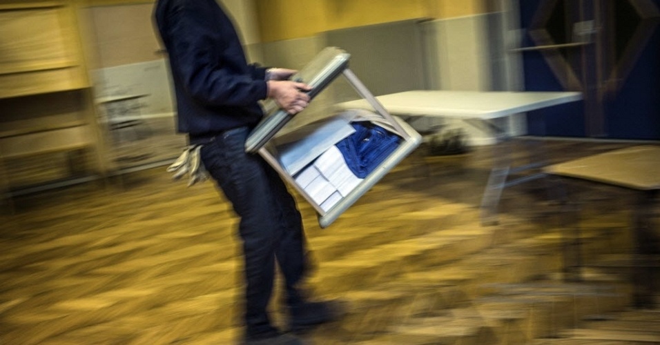Fiscal eleitoral carrega urna em Lyon, na França, que realiza eleições presidenciais no domingo (22)