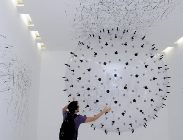 Instalação da artista alemã Karina Smigla-Bobinski permite que o visitante interaja com um globo transparente que flutua pela sala. O globo é coberto por pontas de giz preto, que desenham as paredes brancas da sala - Divulgação