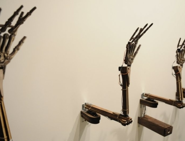 "Please, smile", é uma obra do norte-americano Hye Yeon Nam, que mostra cinco braços robóticos conectados a uma câmera. Assim que o visitante aparece na câmera, os braços imitam os movimentos - Divulgação