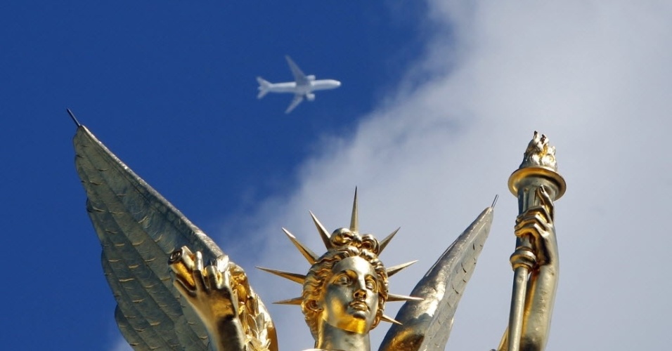 Avião passa no céu sobre a escultura que faz parte do teatro Opera, de Paris (França)