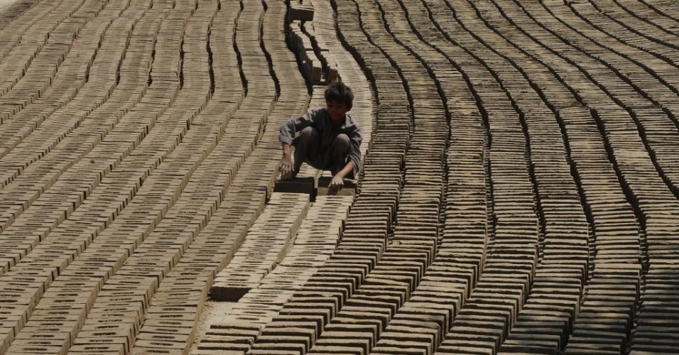 Garoto faz tijolos em olaria da cidade de Lahore, no Paquistão