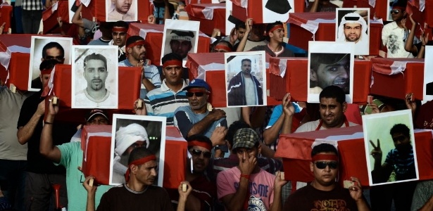 Manifestantes transportam caixões simbólicos com fotos de vítimas da repressão no Bahrein - AFP