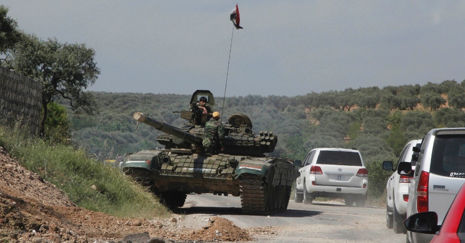 9.mai.2012 - Tanque do Exército sírio escolta carros de observadores da ONU em estrada perto de Idlib. Os observadores iam a locais onde foram registrados protestos contra o ditador sírio, Bashar al Assad