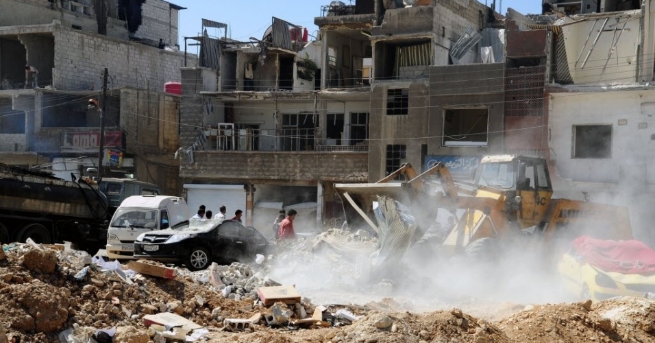 12.mai.2012 - Curiosos observam o que sobrou de prédios atingidos por atentado suicida na Síria