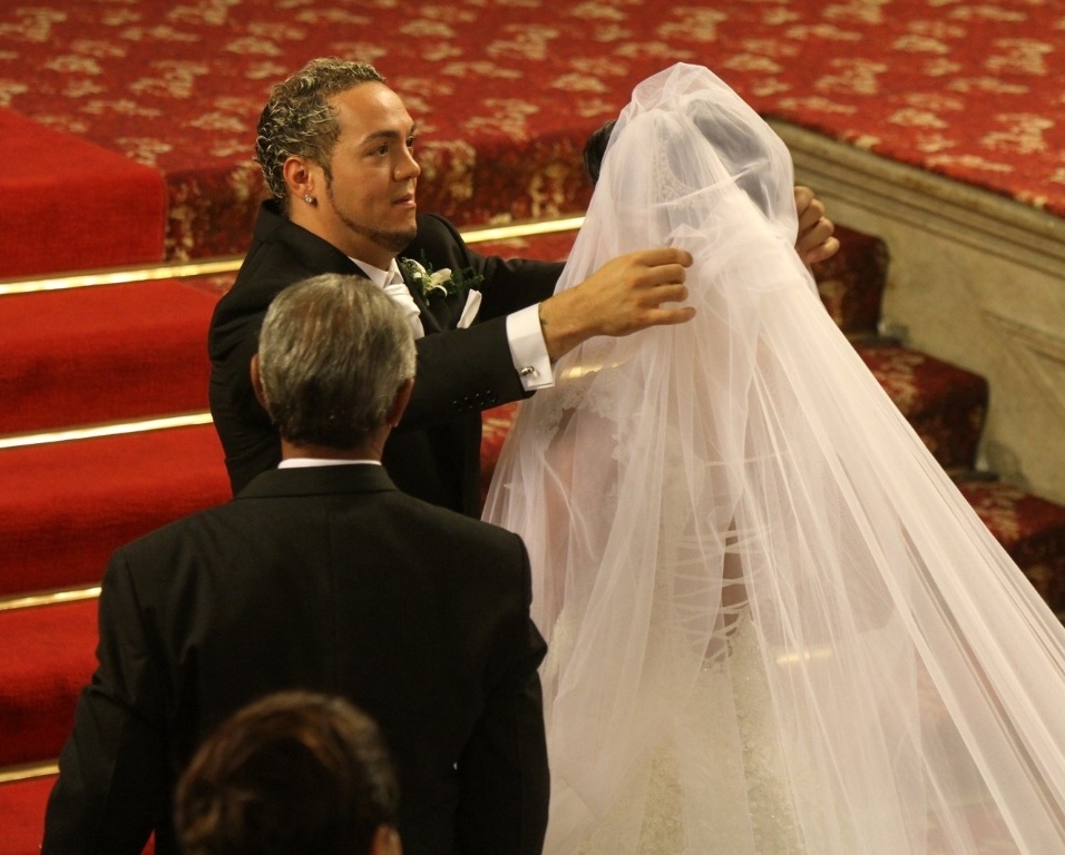 O cantor Belo, no momento em que levanta o véu de Gracyanne Barbosa, o acessório da noiva tem quase três metros de comprimento