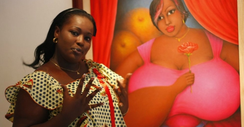 Visitante posa ao lado de obra do pintor Augustin Kassi durante exposição na Costa do Marfim (maio/12) - BBC