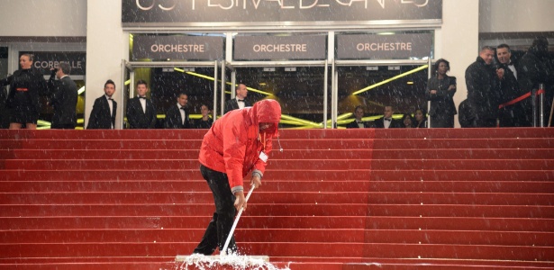 Funcionário retira água do tapete vermelho de Cannes. Uma forte chuva danificou uma das salas do evento e forçou o cancelamento de duas sessões (20/5/12) - AFP Photo/ Anne-Christine Poujoulat