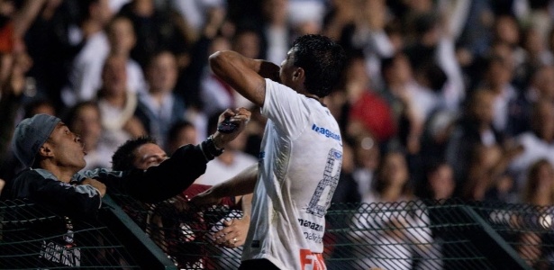 Paulinho sobe no alambrado para comemorar o gol da classificação corintiana à semi - Danilo Verpa/Folhapress