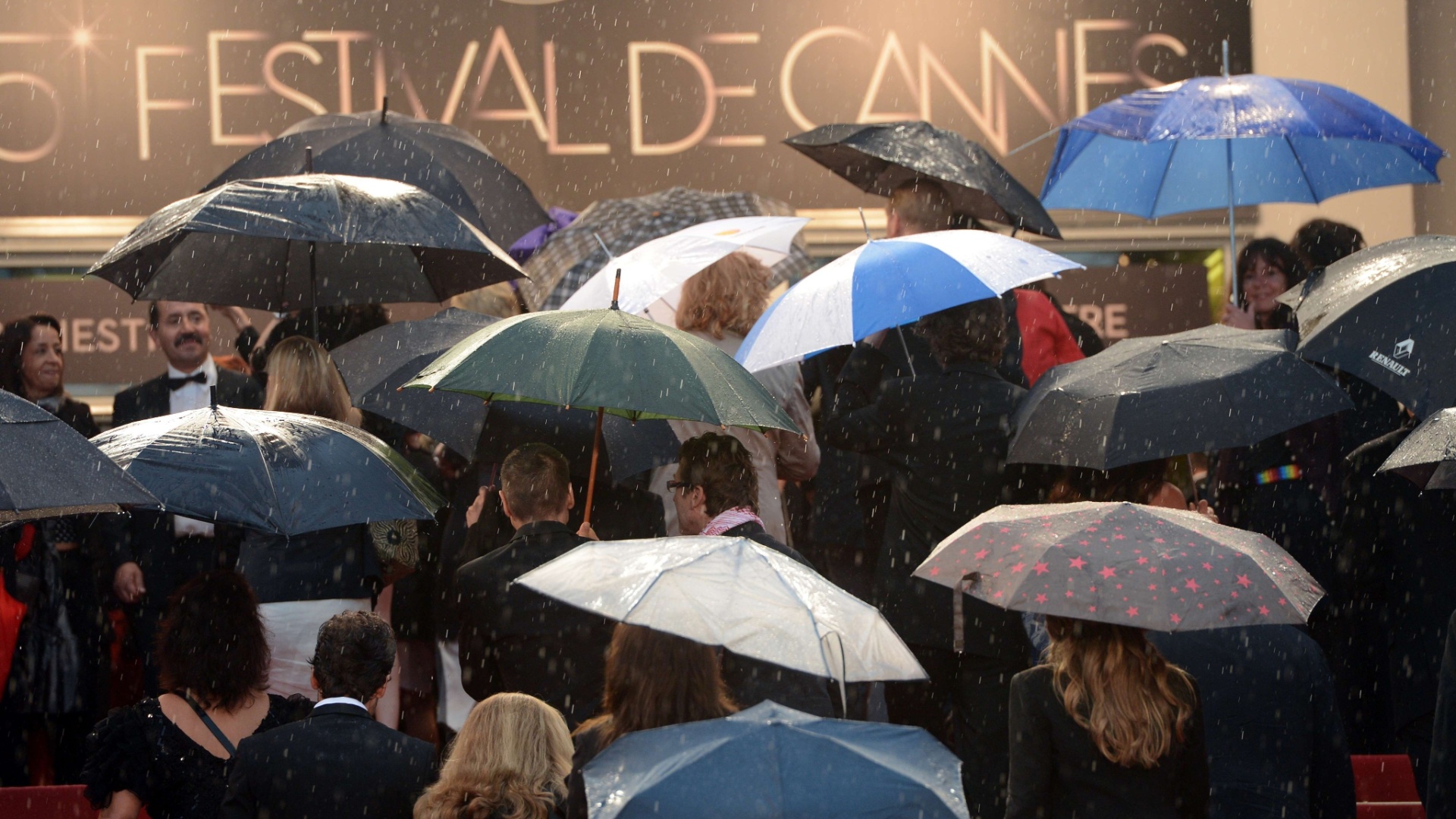 Convidados chegam embaixo de chuva à cerimônia de encerramento da 65ª edição do Festival de Cannes, na França (27/5/12)  - Anne-Chistine Poujoulat/AFP Photo