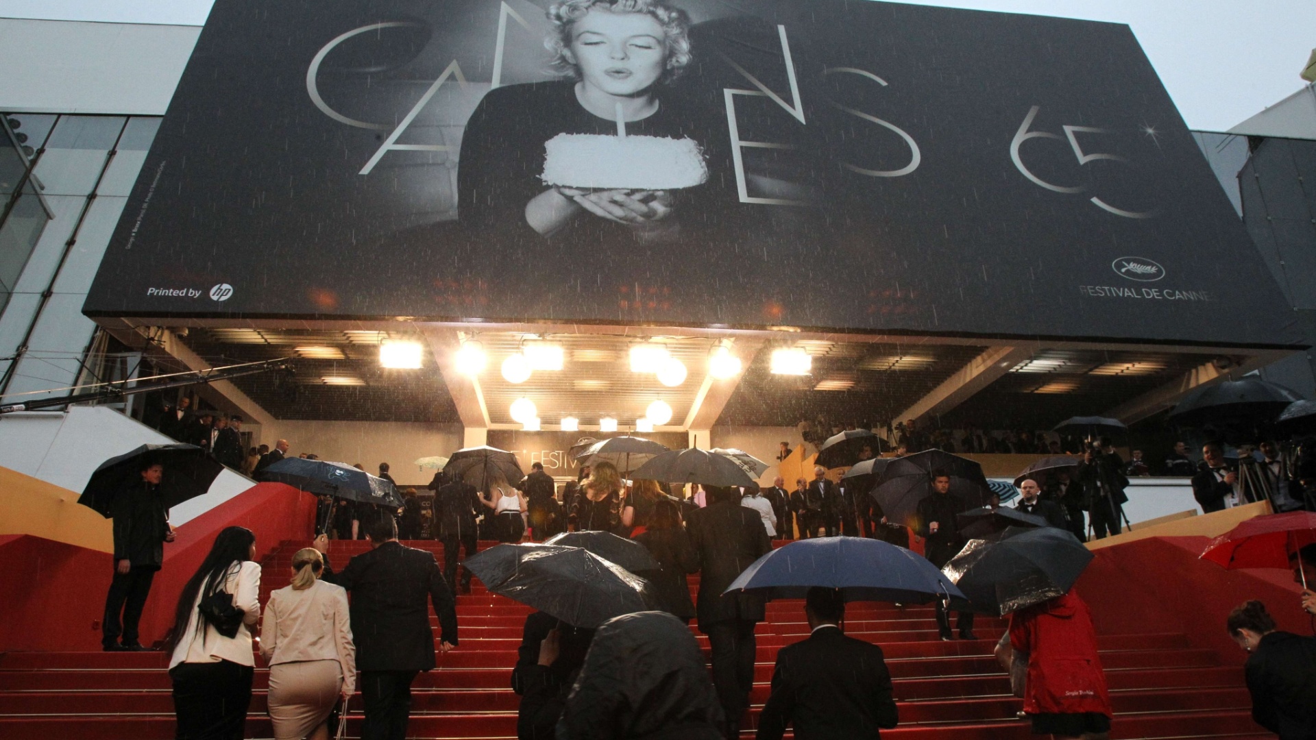 Convidados chegam embaixo de chuva à cerimônia de encerramento da 65ª edição do Festival de Cannes, na França (27/5/12)  - Loic Venance/AFP Photo