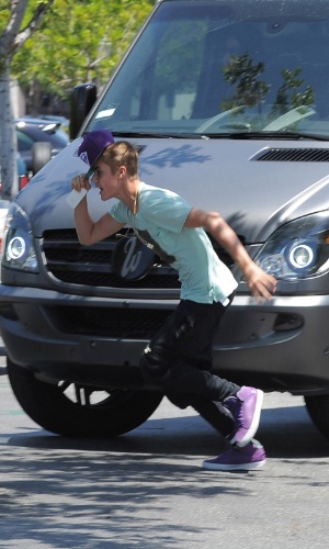 Cantor Justin Bieber corre em direção a fotógrafo ao perceber que estava sendo clicado em saída de shopping center de Los Angeles (27/5/12)
