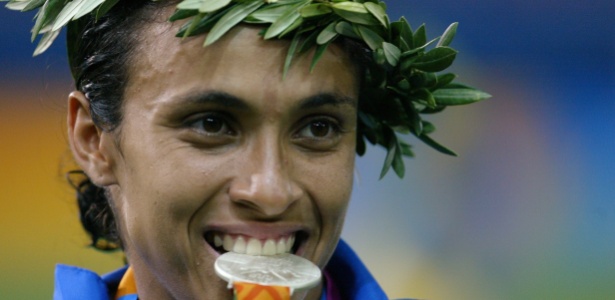 Marta morde a medalha de prata conquistada no futebol nos Jogos Olímpicos de Atenas-2004