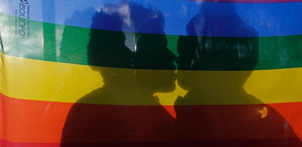 Casal gay coberto por bandeira se beija durante manifestação no Dia Internacional Contra a Homofobia, em Quito, Equador - Dolores Ochoa - 17.mai.2012/AP