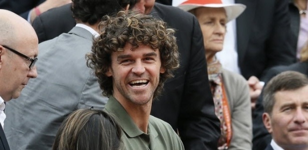 Com a filha no colo, Gustavo Kuerten, o Guga, acompanha jogo em Roland Garros  - AFP PHOTO / PATRICK KOVARIK