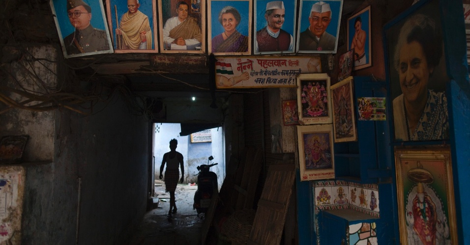 12.jun.2012 - Homem caminha em meio a imagens de ex-políticos indianos e deuses e deusas hindus expostos em rua de Déli, na Índia, durante a madrugada