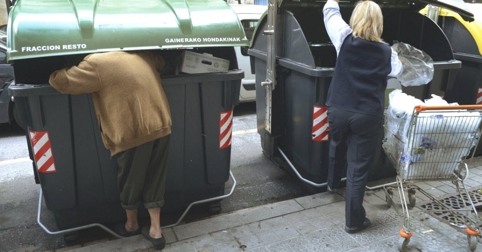12.jun.2012 - Homem (esquerda) vaculha lixo próximo a supermercado na Espanha