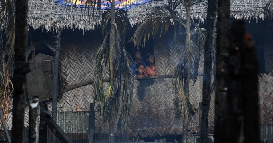12.jun.2012 - Mulher e crianças olham pela janela na cidade de Sittwe, capital do Estado de Rakhine, em Miamar. O governo reformista que tomou posse em 2011 declarou estado de emergência no Estado, onde dezenas já morreram durante uma onda de revoltas eclodidas este ano