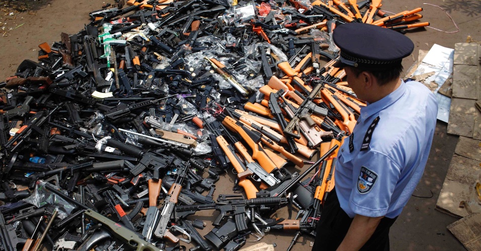 12.jun.2012 - Policial observa armas de brinquedo apreendidas em Xangai, na China