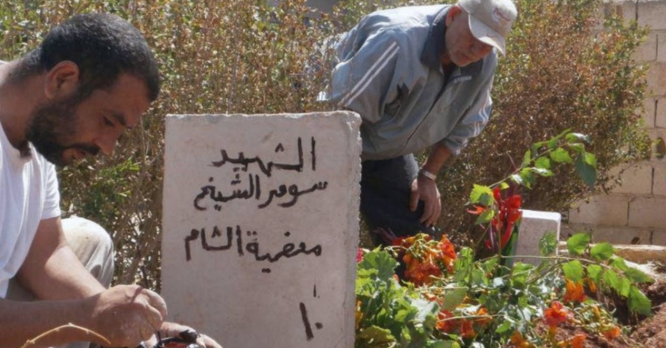12.jun.2012 - Sírios pintam túmulo de vítima supostamente morta pelas forças do regime do ditador Bashar al-Assad
