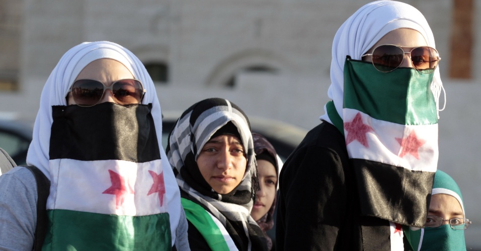 13.jun.2012 - Mulheres sírias que moram na Jordânia protestam contra o ditador Bashar al Assad usando bandeiras da oposição síria no rosto, em Amã, capital da Jordânia