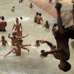 Jovens indianos se refrescam em um canal em Amritsar, na Índia - Narinder Nanu/AFP