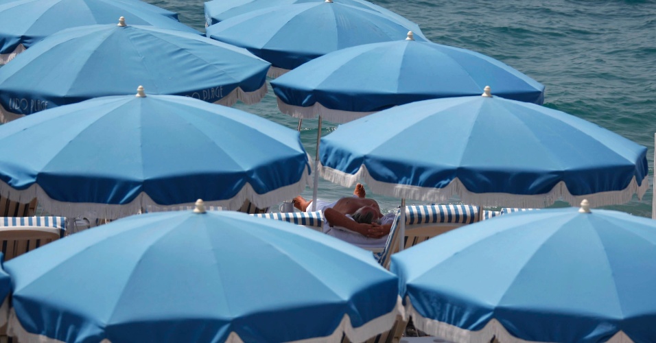 29.jun.2012 Um homem relaxa na sombra de guardas-sol em uma praia da Promenade des Anglais, com temperaturas de 30 graus Celsius, em Nice