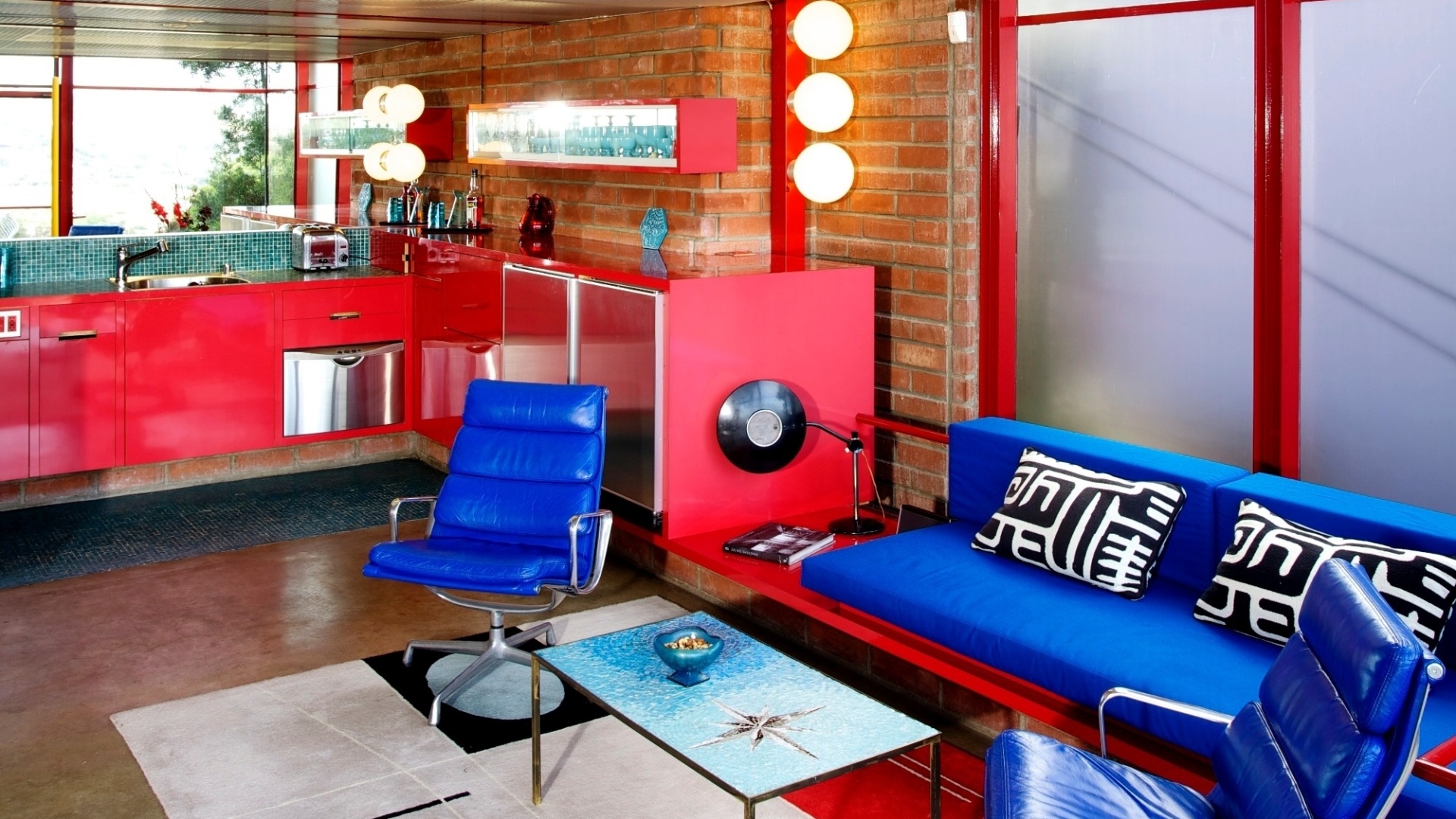 Na sala de estar da casa de Patricia Marks, uma mesa de centro, também em mosaico de cerâmica azul turquesa, e as cadeiras Eames Aluminum. Com 95 m², a residência foi projetada pelo arquiteto Allyn Morris  - Ethan Pines/The New York Times