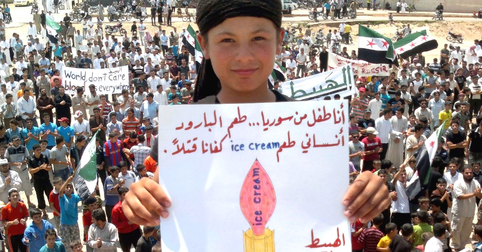 30.jun.2012 - Garoto sírio segura cartaz com a mensagem "Eu sou uma criança da Síria... O gosto de pólvora esqueceu o gosto do sorvete. Parem de matar""