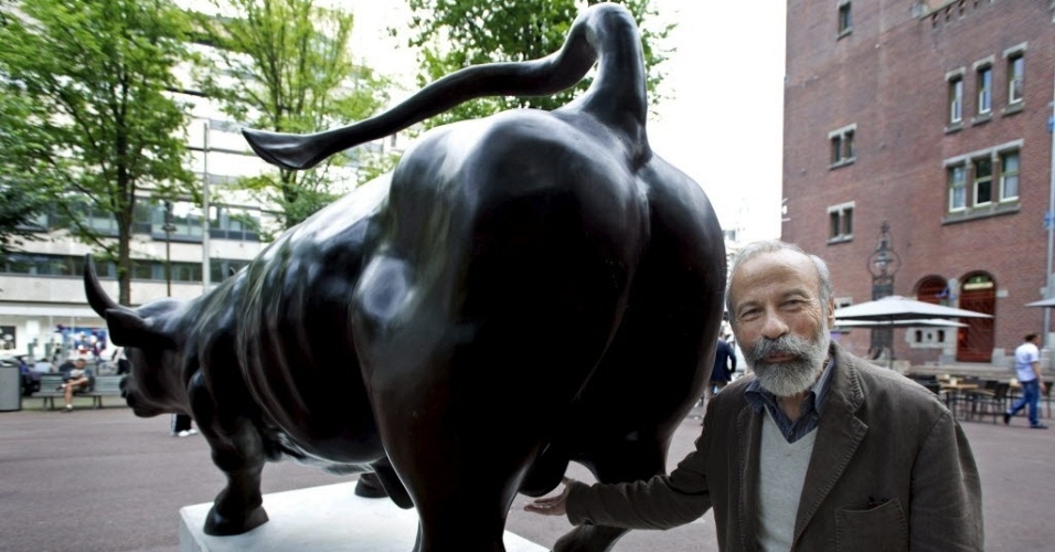 5.jul.2012 - Artista ítalo-americano Arturo de Modica posa ao lado de sua escultura de touro em bronze, em exibição na praça Beursplein, na capital da Holanda, Amsterdã