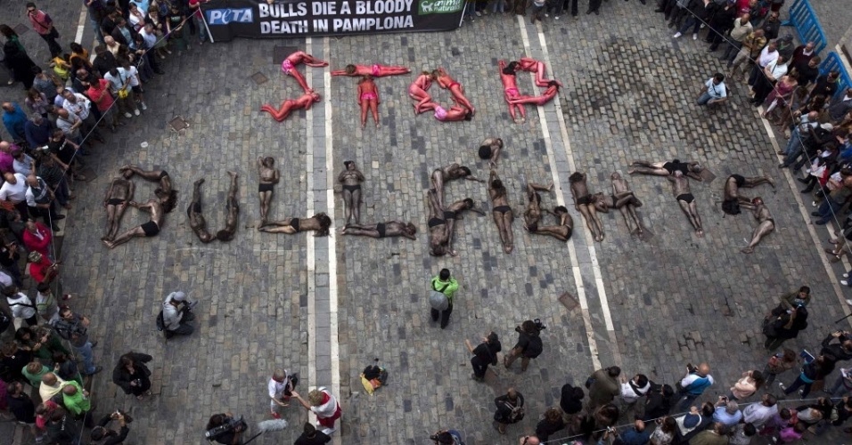 5.jul.2012 - Cobertos de sangue falso, manifestantes formam a frase "Stop Bullfights" ("Parem a matança de touros", em inglês) durante protesto em Pamplona, na Espanha