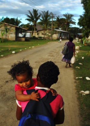 Menina caminha pelas ruas de Sigatoka, em Fiji, com a irmã no colo. O país é comandado por Commodore Josaia Bainimarama desde 2006, quando foi instaurado um golpe militar  - Andrew Quilty / International Herald Tribune