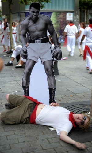 7.jul.2012 - Participante da festa de São Firmino, na Espanha, posa deitado em frente à imagem do boxeador Muhhamed Ali