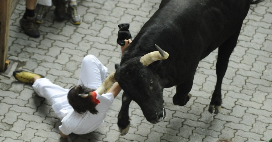 7.jul.2012 - Touro arrasta participante pela camisa durante a festa de São Firmino, em Pamplona, na Espanha