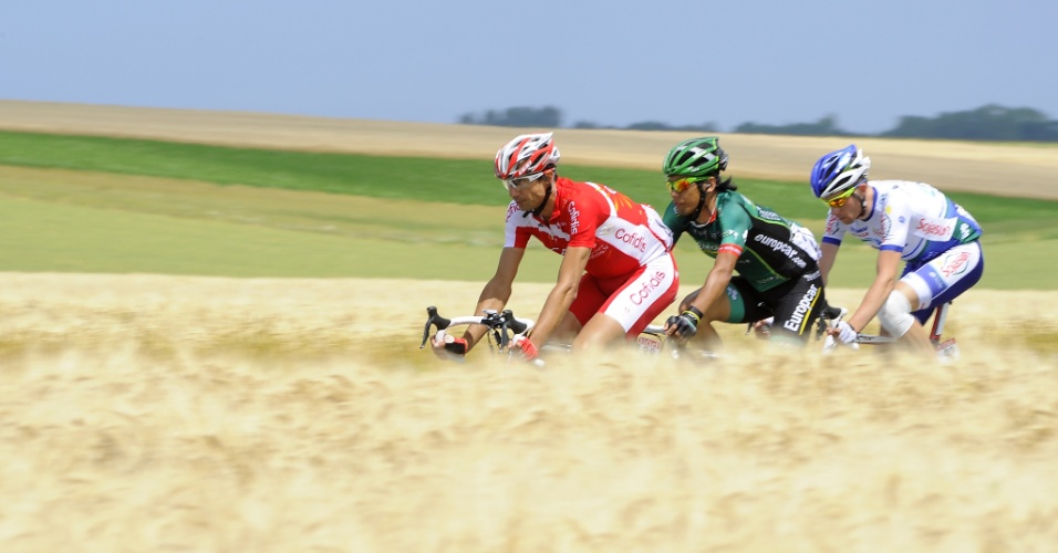 Ciclistas do Tour pedalam em meio a plantações existentes nas margens da pista