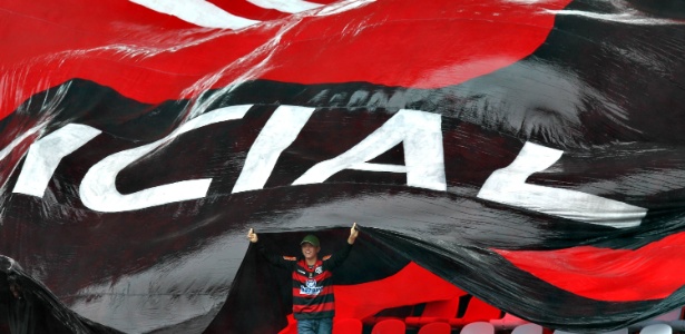 Torcedor se protege da chuva debaixo de bandeira do Flamengo antes de clássico - Julio Cesar Guimarães/UOL