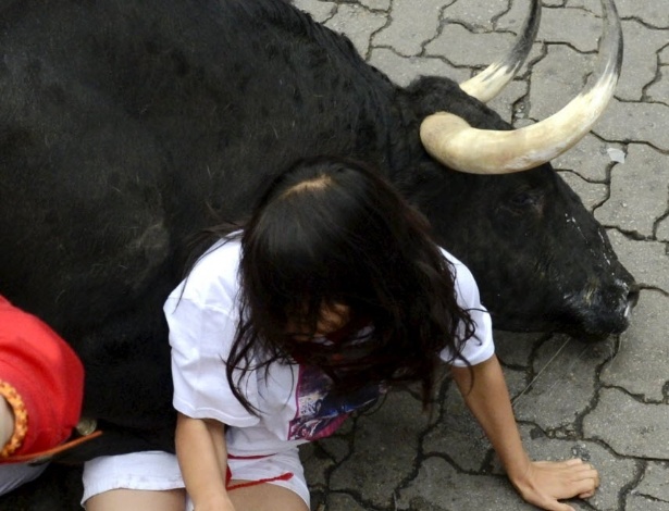 9.jul.2012 - Garota é atingida por touro durante quarto dia da Festa de São Firmino, em Pamplona, na Espanha 