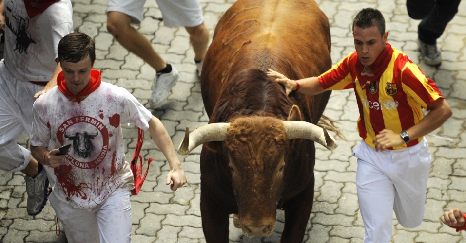 10.jul.2012 - Espanhol corre ao lado de touro durante tourada tradicional da Festa de São Firmino, realizada na cidade espanhola do norte de Pamplona. O festival é um símbolo da cultura espanhola, que atrai milhares de turistas, apesar da condenação pesada de grupos de direitos dos animais