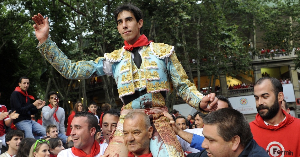 11.jul.2012 - Sujo de sangue e com a calça rasgada, mas orgulhoso, o toureiro Saul Jimenez Fortes sai carregado  da arena de Pamplona na quarta-feira (11)