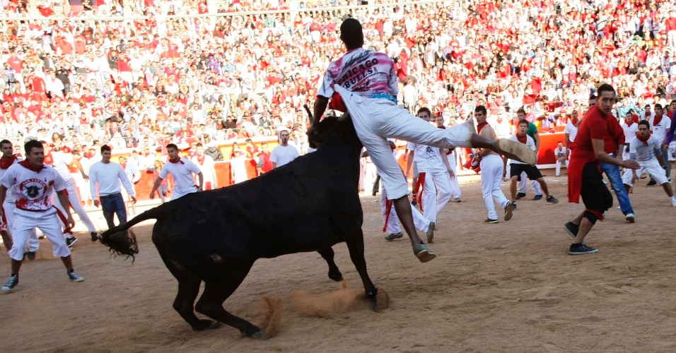 12.jul.2012 - Homem se agarra no chifre da vaca, em comemoração na arena de Pamplona, no sexto dia do Festival de São Firmino, na Espanha