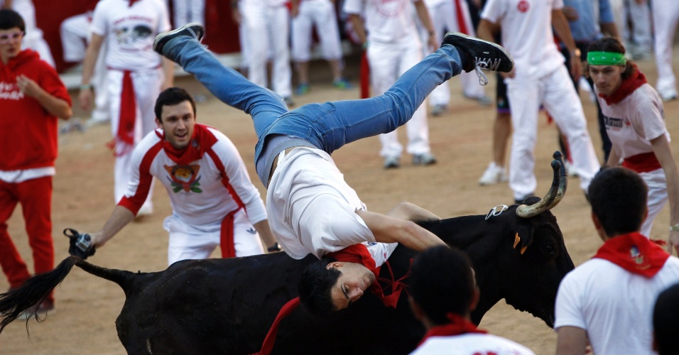 12.jul.2012 - Rapaz arrisca performance sobre a vaca solta na arena de Pamplona, no sexto dia do Festival de São Firmino, na Espanha