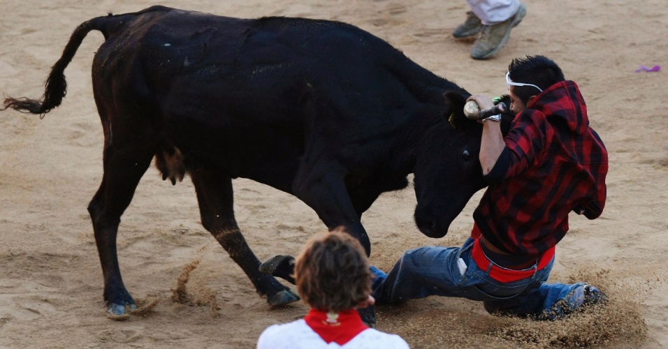13.jul.2012- Folião agarra o chifre da vaca durante a corrida da sexta-feira (13) na arena de Pamplona, no Festival de São Firmino